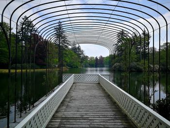 Footbridge over lake against trees