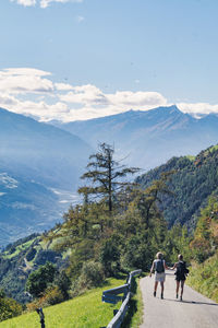 Rear view of women walking on mountain against sky