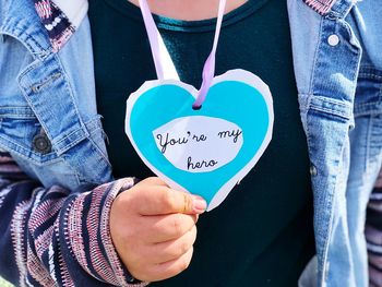 Midsection of woman holding heart shape with text