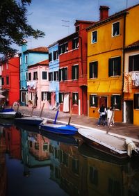 Boats moored in canal by buildings in city