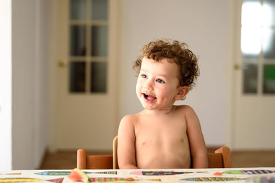 Portrait of shirtless boy sitting at home