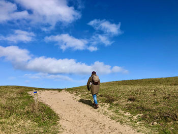 Full length of woman walking on field against sky