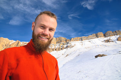 Portrait of man standing on snow covered mountain against sky