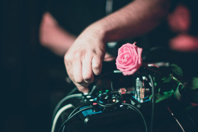 Cropped hands of man with pink rose on sound recording equipment in nightclub