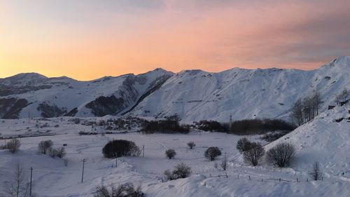 Scenic view of snow covered mountains against sky during sunset