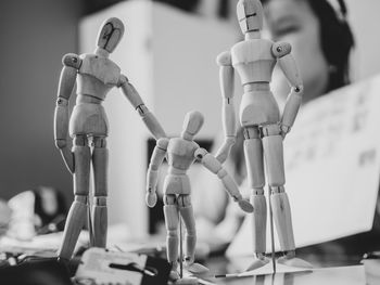 Close-up of wooden figurines with girl in background at home