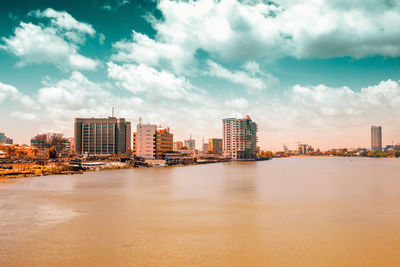 River by buildings in city against sky