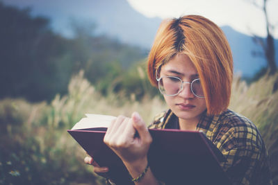 Young woman sitting reading a book at nature in the evening.