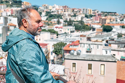 Handsome mature bearded man enjoying a view of panorama of messina, sicily, italy. urban traveling