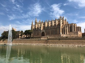 Reflection of building in lake against cloudy sky