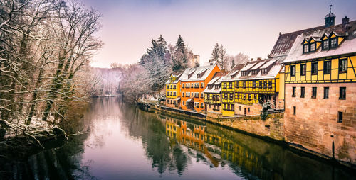 Scenic view of river by buildings against sky