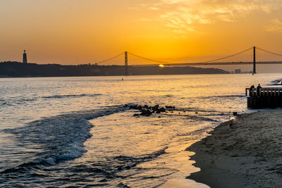 Suspension bridge over sea during sunset