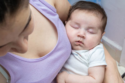 Beautiful latin baby girl sleeping tenderly in her mother's arms while mom looks away. 