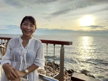 Portrait of smiling man standing at sea shore against sky