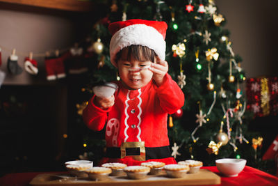 Smiling girl preparing cookies on table during christmas