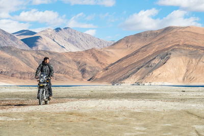 Man riding bicycle on mountain against sky