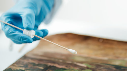 Oil painting cleaning, female conservator removing dirt from an old oil painting