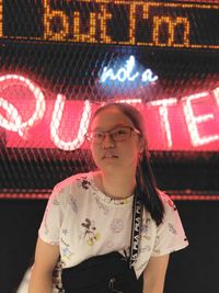 Portrait of woman standing against illuminated wall