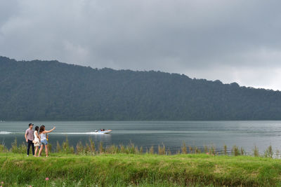 People on shore against sky