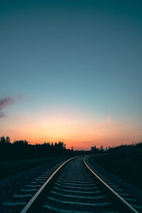 Empty road against clear sky at sunset