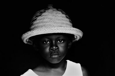 Portrait of man wearing hat against black background