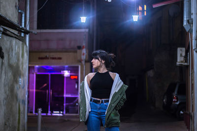 Rear view of woman standing in illuminated city at night