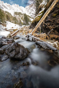 Stream flowing through snow covered rocks
