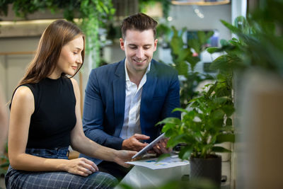 Young business persons having discussion while holding digital tablet sitting at cafe