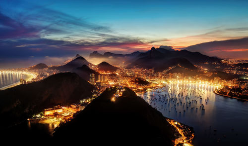 Illuminated city against sky during sunset