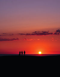 Silhouette people standing on land against sky during sunset