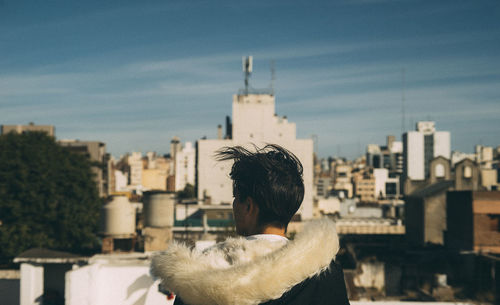 Rear view of man and buildings against sky