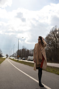 Full length of woman standing on road against sky