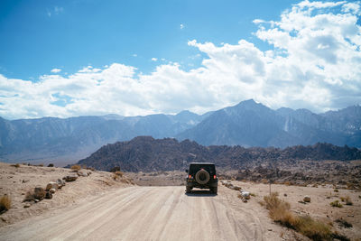 Car on road by mountains against sky