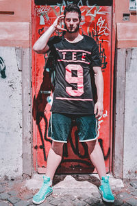 Portrait of young man standing against door