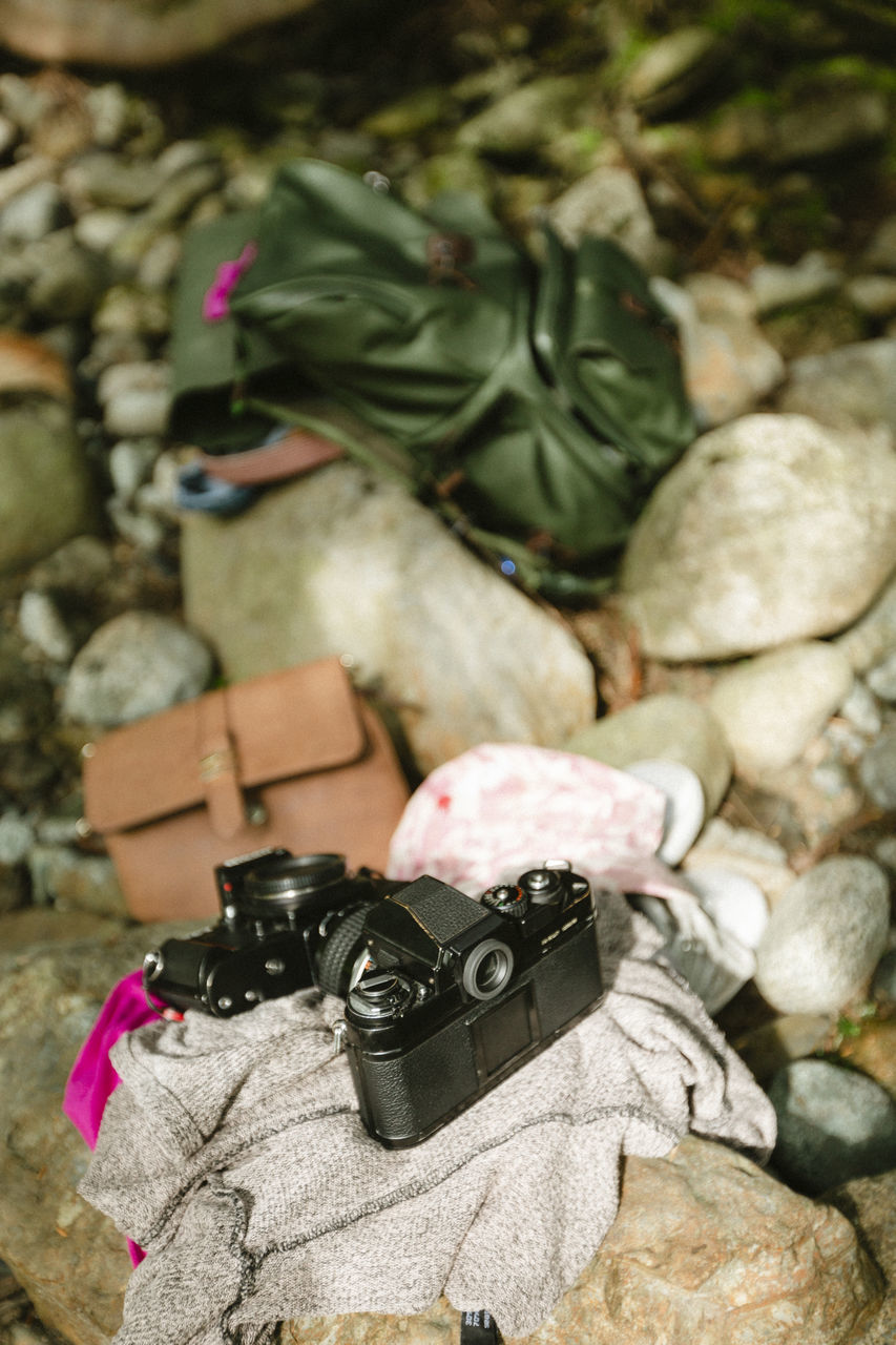 HIGH ANGLE VIEW OF CAMERA AND ROCK ON LAND