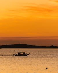 Silhouette boat in sea against orange sky