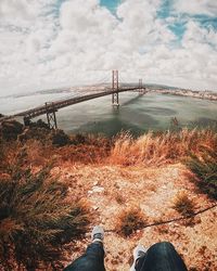 Low section of man on bridge against sky