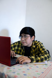 Portrait of man using mobile phone while sitting on table