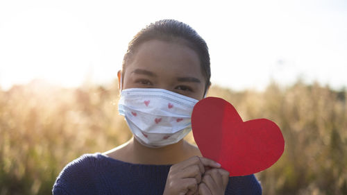 Close-up portrait of a beautiful young woman holding heart