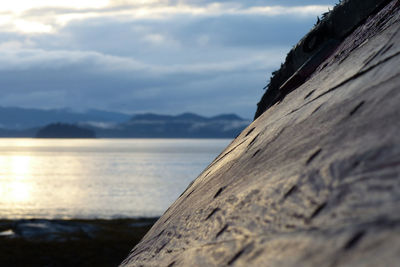 Close-up of stone wall by sea against sky