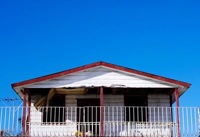 Low angle view of broken house against clear blue sky