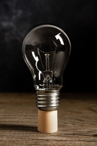 Close-up of light bulb on table against black background