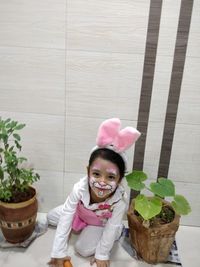 Portrait of a smiling girl sitting on potted plant