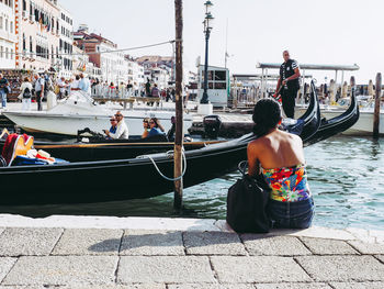 Rear view of woman sitting on boat in canal