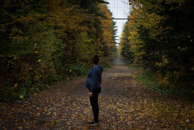 Rear view of man walking on road in forest