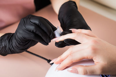 Manicurist treats the client's nail with a degreasing liquid to prepare nails for manicure
