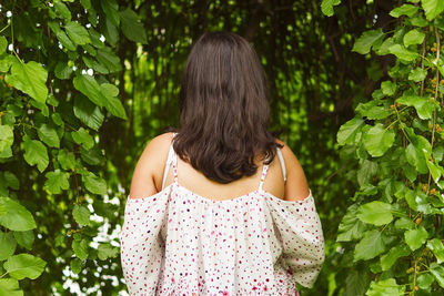 Rear view of teenage girl standing against plants