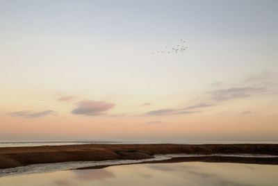 Scenic view of beach against sky during sunset