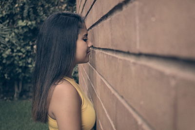 Side view of beautiful woman standing by wall