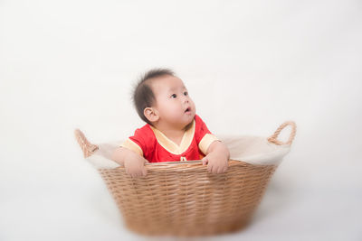 Cute boy looking away in basket against white background